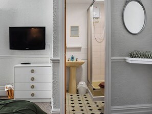 A bathroom with a shower, sink, toilet, and a television mounted on the wall. - A spacious property perfect for families and friends. (Bispham, near Blackpool)