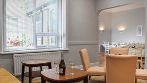 A dining area with a table set for two, a chair, and a bottle of wine on the table. - A spacious property perfect for families and friends. (Bispham, near Blackpool)