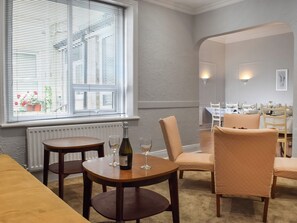 Un coin repas avec une table dressée pour deux personnes, une chaise et une bouteille de vin posée sur la table.