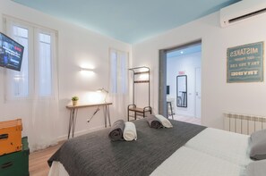 Relax in a serene space with a neatly made bed, desk, and wall-mounted TV.