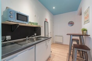 Compact kitchen with microwave, sink, and white cabinets.