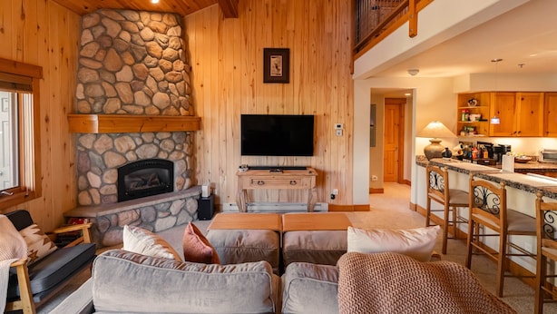 A cozy living room with a stone fireplace, a flat-screen TV, and comfortable seating.