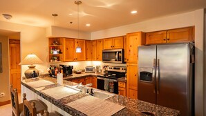 A kitchen with granite countertops, wooden cabinets, stainless steel appliances, and a built-in oven.