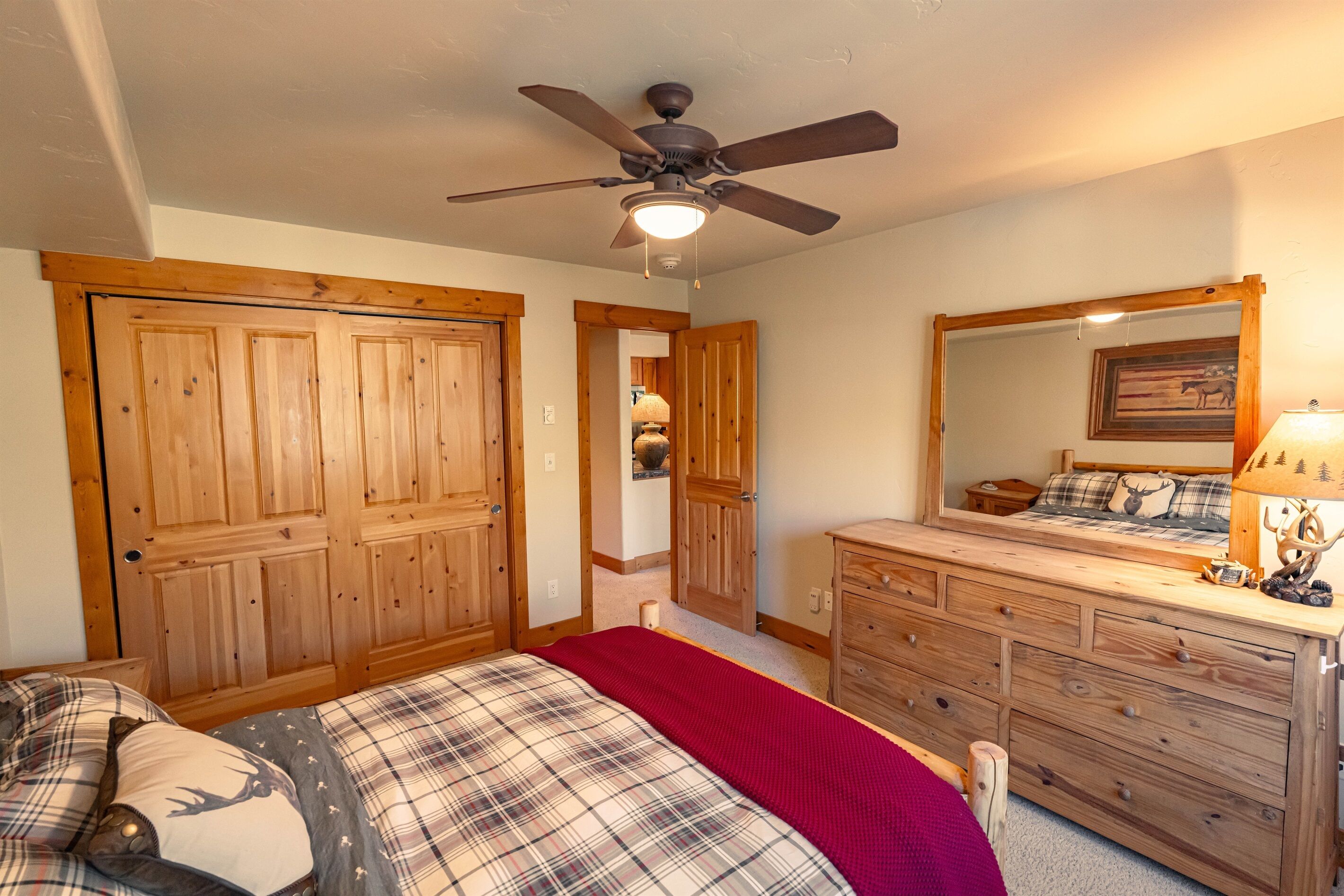 Ein Schlafzimmer mit Bett, Holzschrank, Schminktisch und Deckenventilator.