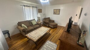 Ein Wohnzimmer mit einem braunen Sofa, einem kleineren Sofa, einem Couchtisch und einer TV-Bank.
