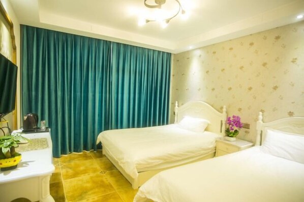 A hotel room with two beds, a desk, a chair, a television, and a curtain.
