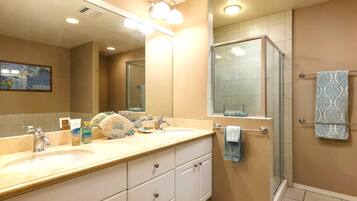 A bathroom with two sinks, a glass shower, and a towel rack.