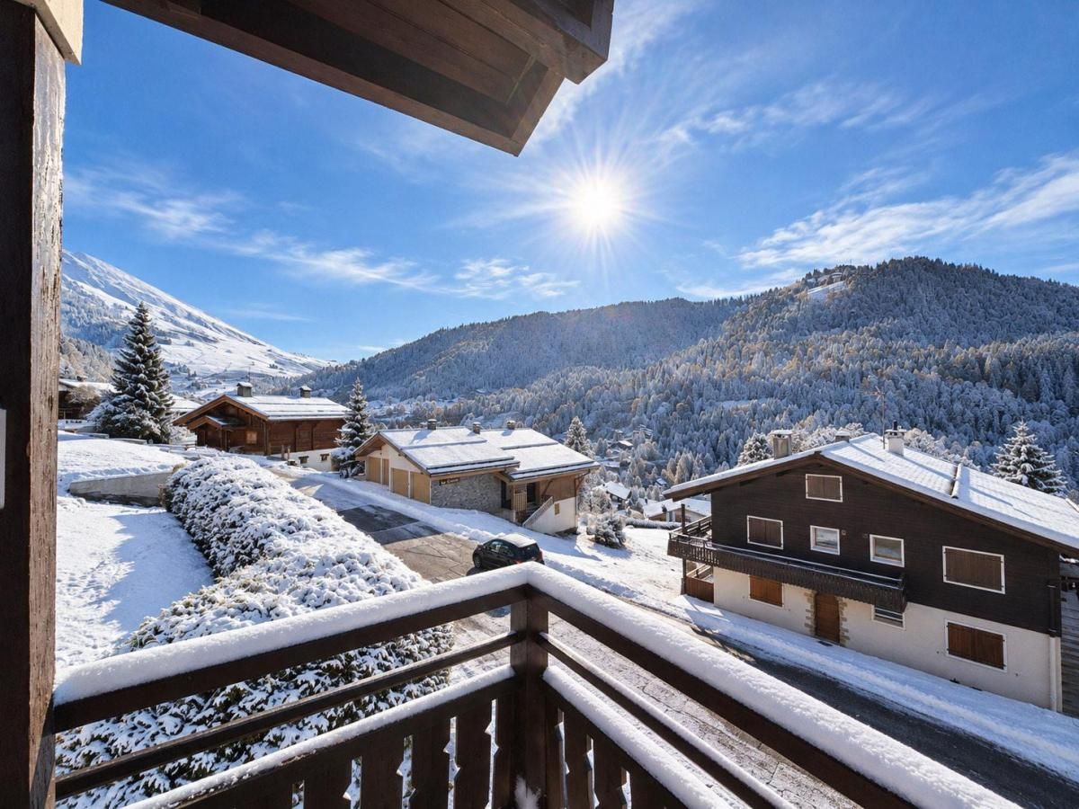 A snow-covered mountain landscape with buildings and a wooden balcony.