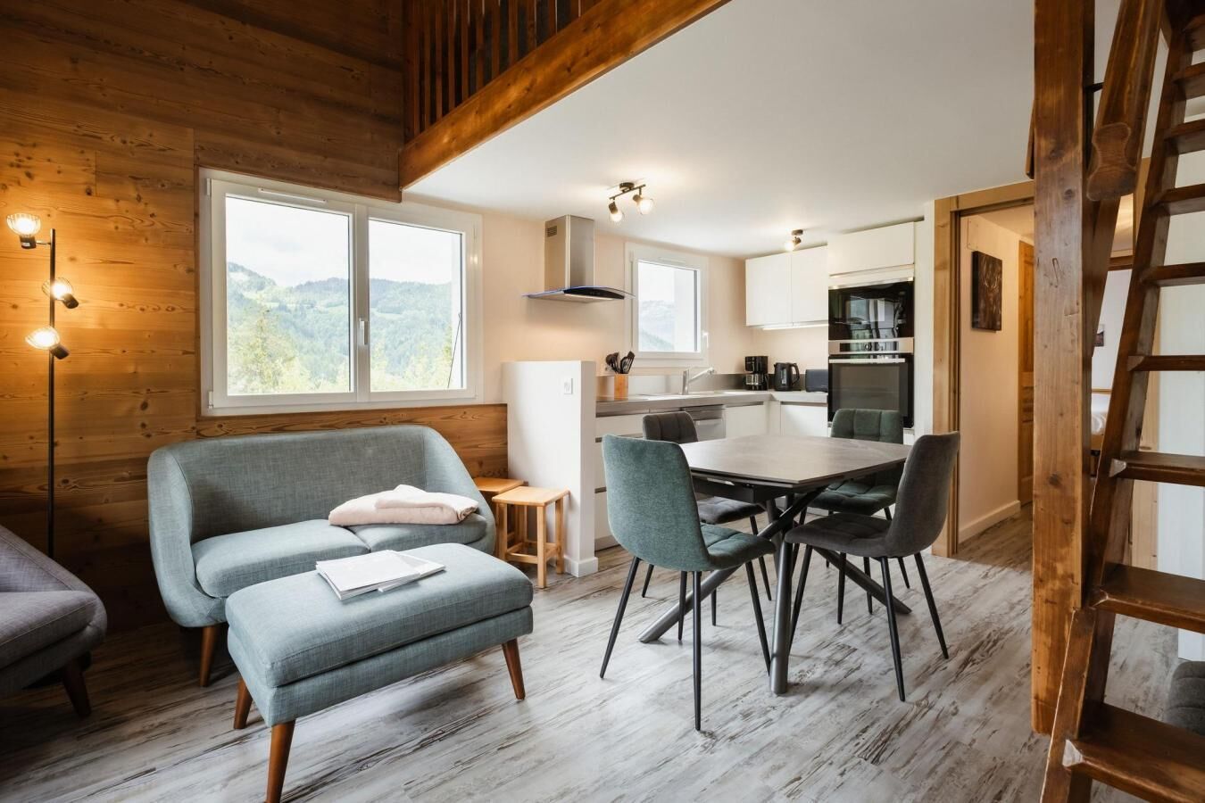 Une pièce confortable avec un canapé, une table à manger et des chaises, un coin cuisine et une vue sur l’extérieur.