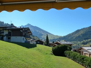 A residential area with houses on a hillside, a mountain in the background, and a clear sky. - 1st floor, view mountain, balcony, fireplace or stove, tv, ski locker, 55m², La Clusaz (La Clusaz)
