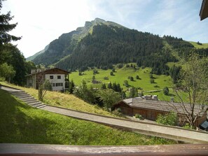 Eine Berglandschaft mit einer Straße, einem modernen Gebäude und einem traditionellen Holzhaus.