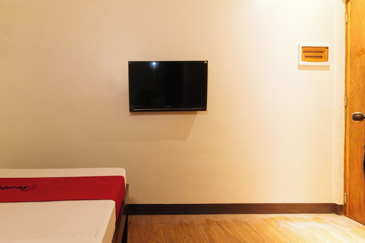 Een hotelkamer met een bed, een wandtelevisie en een houten deur.