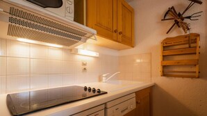 A kitchen with a Bosch stove, white tiles, wooden cabinets, and a hanging utensil rack.