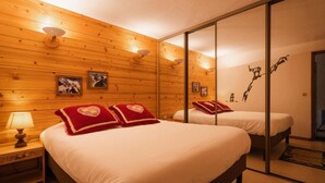 A hotel room with two beds, wooden walls, and a mirror.
