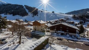 A snow-covered village with traditional wooden buildings, a clear sky, and a mountain backdrop.