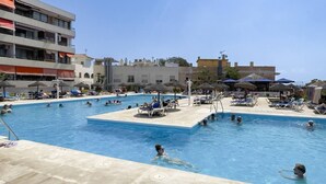 Une piscine avec plusieurs couloirs de nage, des chaises longues et des parasols.