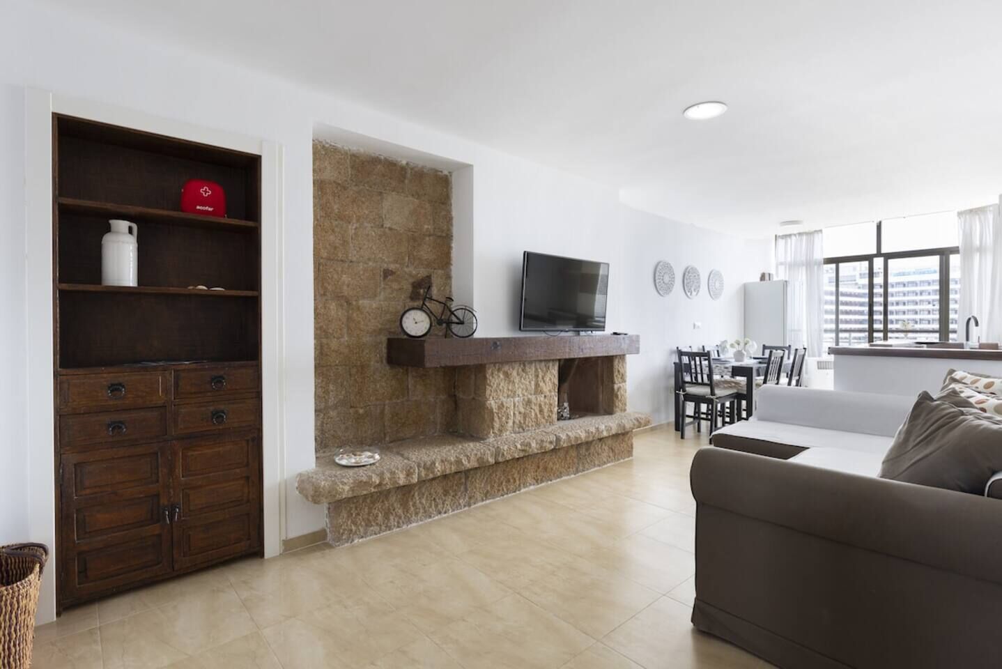 Een woonkamer met een stenen openhaard, een televisie en een eethoek met een tafel en stoelen.