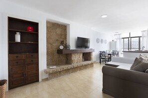 Un salón con chimenea de piedra, televisor y comedor con mesa y sillas.