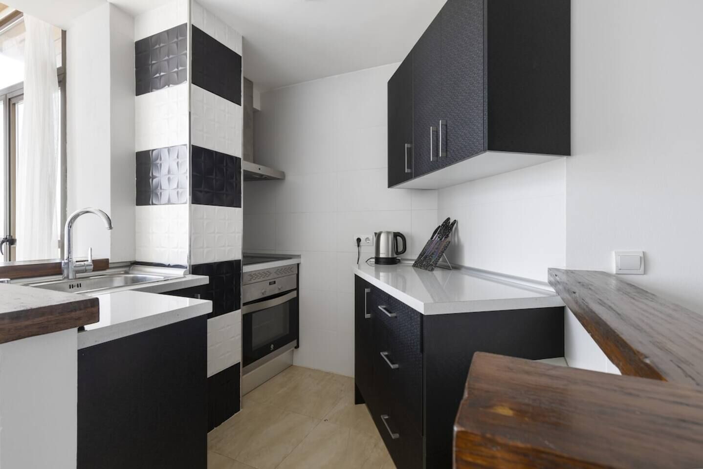A modern kitchen with a built-in oven, a sink, and a coffee maker.