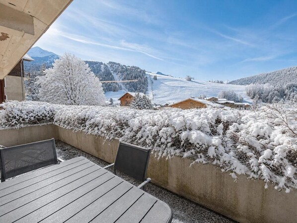 An outdoor seating area with a view of a snowy landscape and mountains.