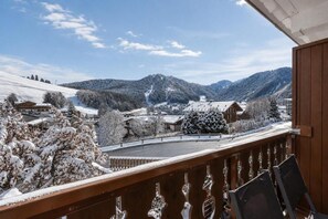 A snowy mountain landscape with a wooden balcony overlooking a village.