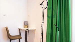 A room with a chair, a small table with a lamp, a green curtain, and a microphone stand. - St. Agnes Hannibal (Roma)
