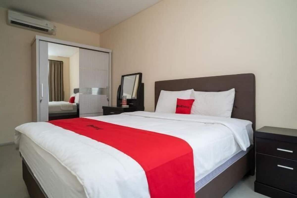 Ein Hotelzimmer mit Bett, Nachttisch, Kommode und Spiegel.