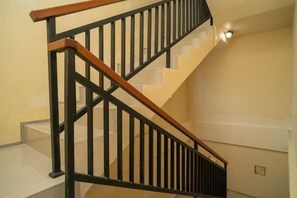 A staircase with a wooden handrail and black balusters. - RedDoorz near ITDC Nusa Dua (Bali)