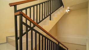 A staircase with black railings and wooden handrails. - RedDoorz near ITDC Nusa Dua (Bali)