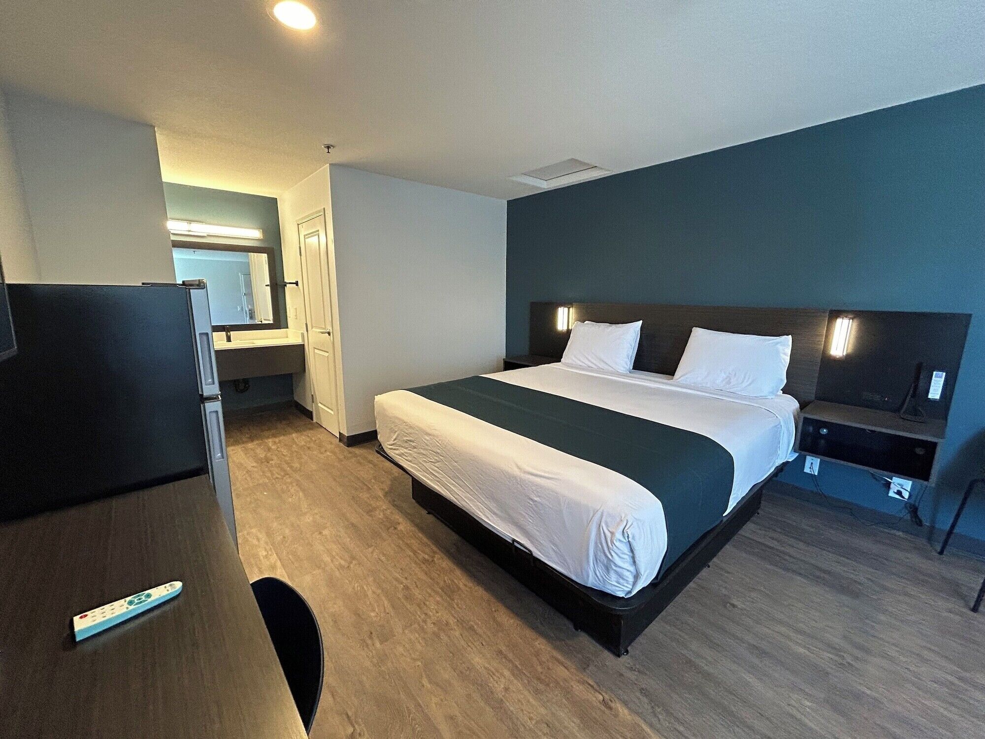 Een hotelkamer met een bed, een bureau, een stoel, een kast en een spiegel.