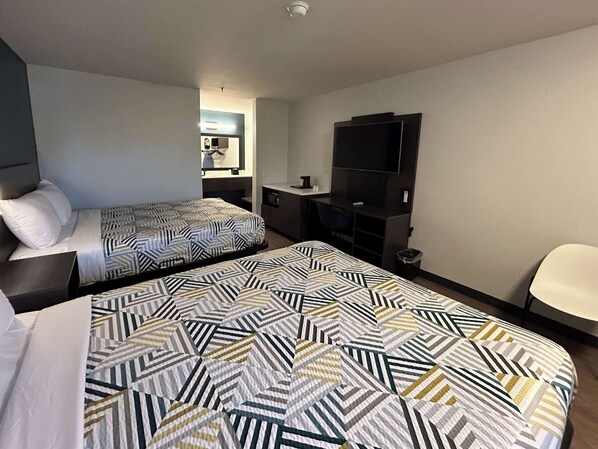 Une chambre d’hôtel avec deux lits, une télévision, un bureau et une chaise.