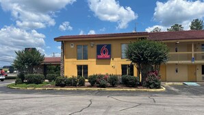 A motel with a red-tiled roof, a sign indicating it is a motel and studio, and a handicap-accessible entrance. - Studio 6 Extended Stay - Huntsville, AL University Drive (Huntsville)