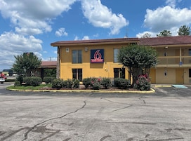 A motel with a red-tiled roof, a sign indicating it is a motel and studio, and a handicap-accessible entrance.