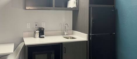 A compact kitchen with a microwave, coffee maker, and a toaster on the counter.