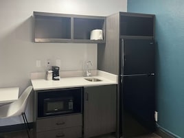 A compact kitchen with a microwave, coffee maker, and a toaster on the counter.