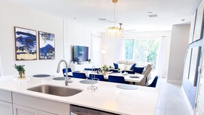 A modern kitchen with a central island, built-in dishwasher, and a dining area with a sofa and table. - RR7858 - The Minions @ Reunion - 8 guests (Kissimmee)