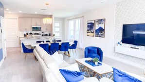 A modern living room with a white sofa, blue chairs, a coffee table, and a TV on the wall. - RR7858 - The Minions @ Reunion - 8 guests (Kissimmee)