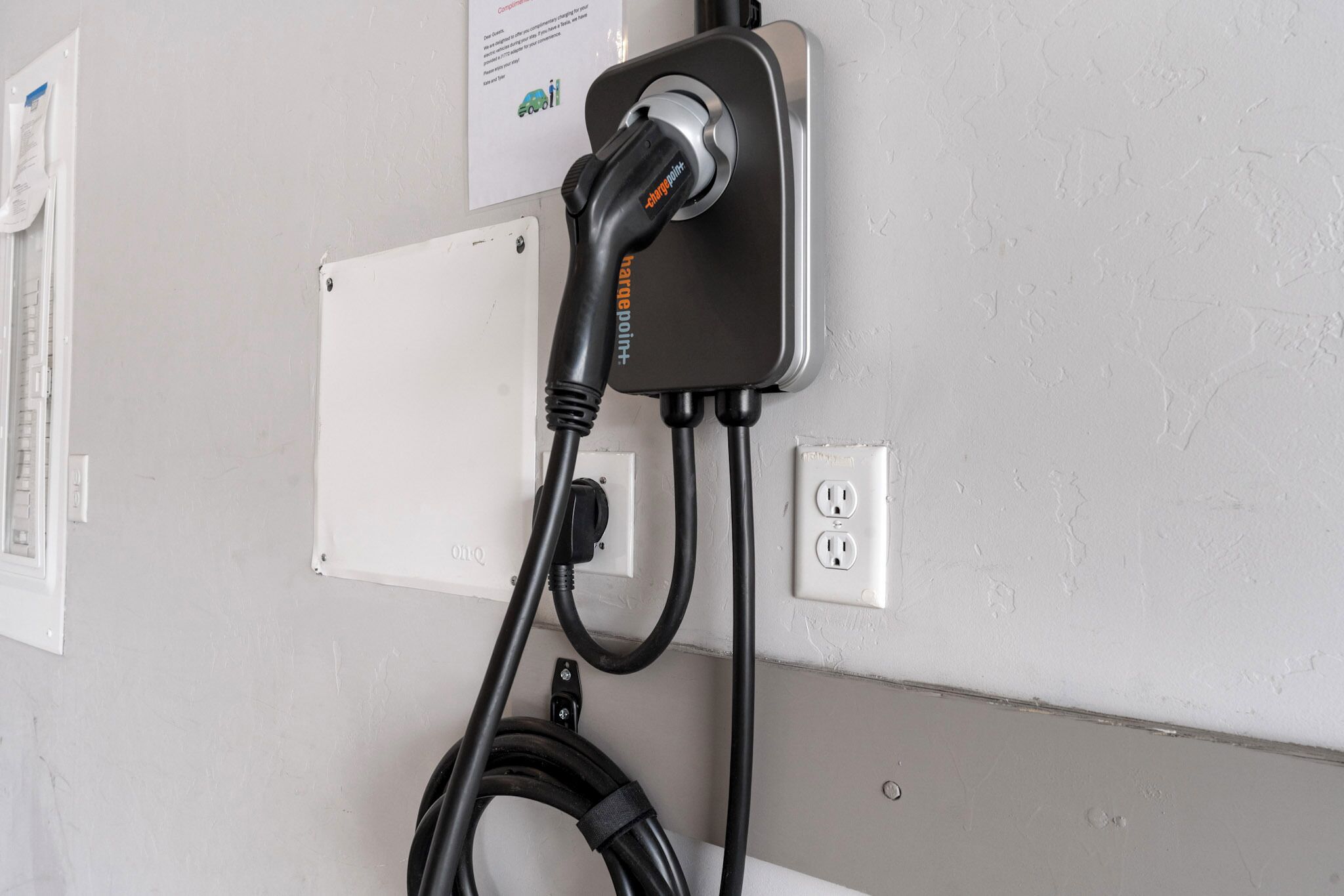 Une borne de recharge dotée d’un câble branché sur une prise murale.