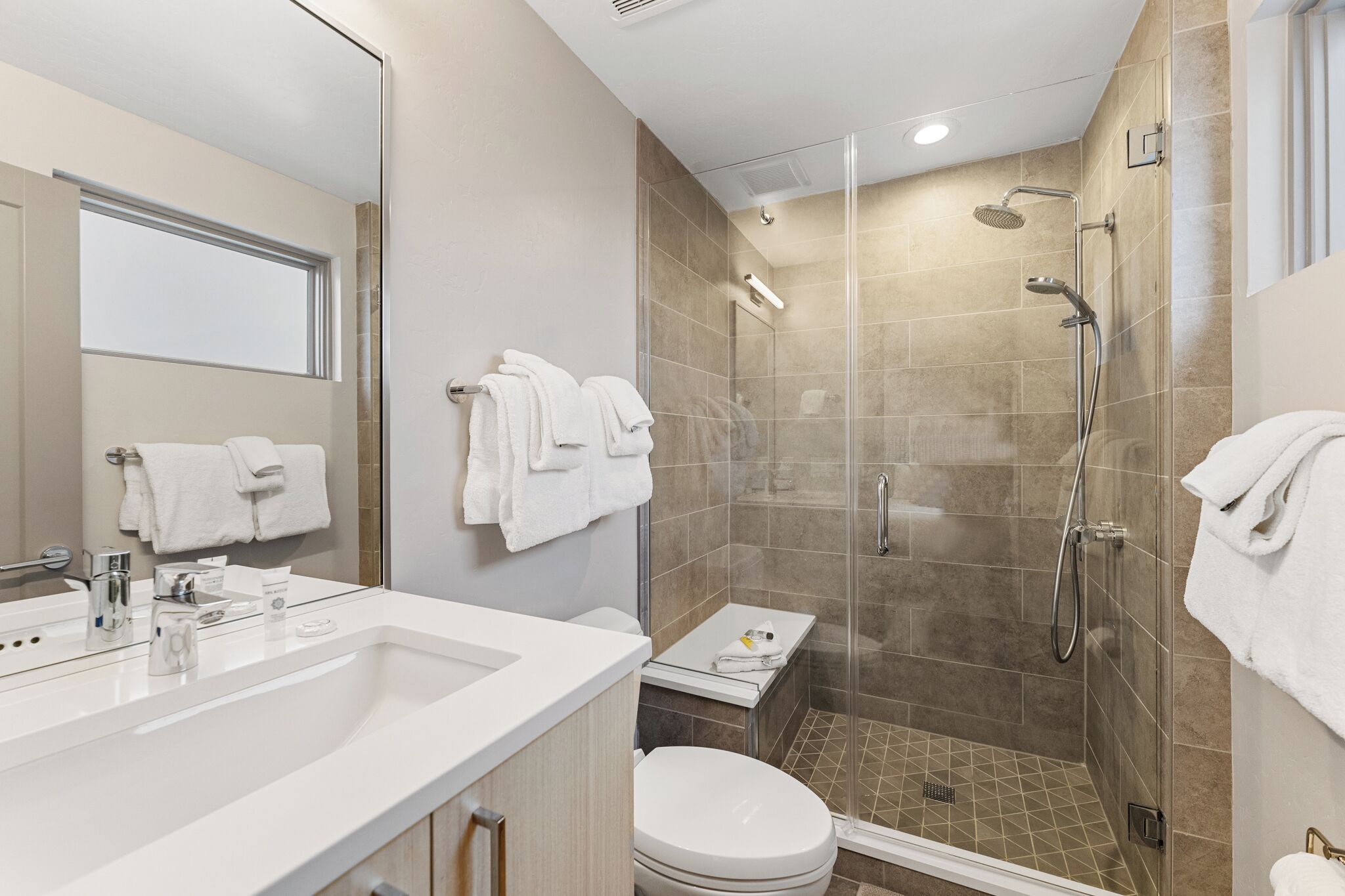 A modern bathroom with a glass-enclosed shower, a white sink, and a toilet.