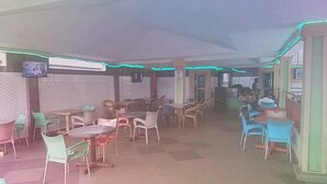 Un comedor con mesas y sillas, un televisor montado en la pared y un papel tapiz decorativo.