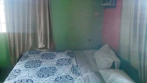 Una habitación con una cama, una ventana con cortinas y un aire acondicionado de pared.