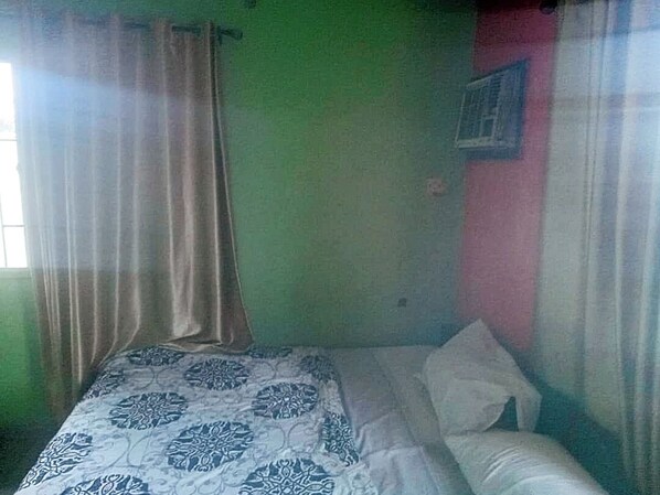 Una stanza con un letto, una finestra con tende e un condizionatore d'aria a parete.