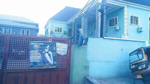 Un edificio con fachada azul, una verja roja y un letrero que anuncia un lounge y bebidas.