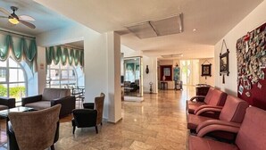 A spacious lobby with leather seating, a ceiling fan, and a wall adorned with framed pictures. - Hotel Albora (Kusadasi)