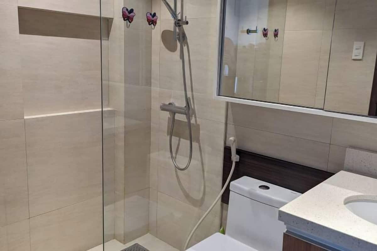 A modern bathroom with a glass-enclosed shower, a white toilet, and a large mirror.