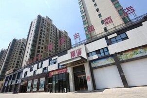 Un hotel de varios pisos, con una entrada destacada y un letrero grande con letras rojas.
