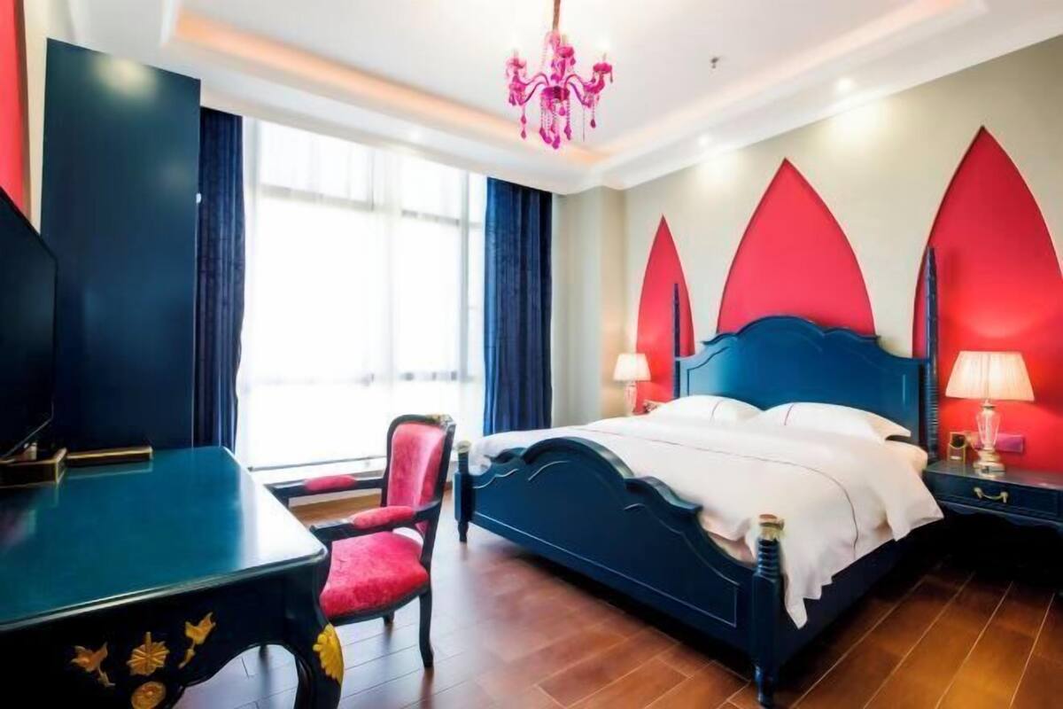 Une chambre d’hôtel avec un lit, un bureau, une chaise et un téléviseur.