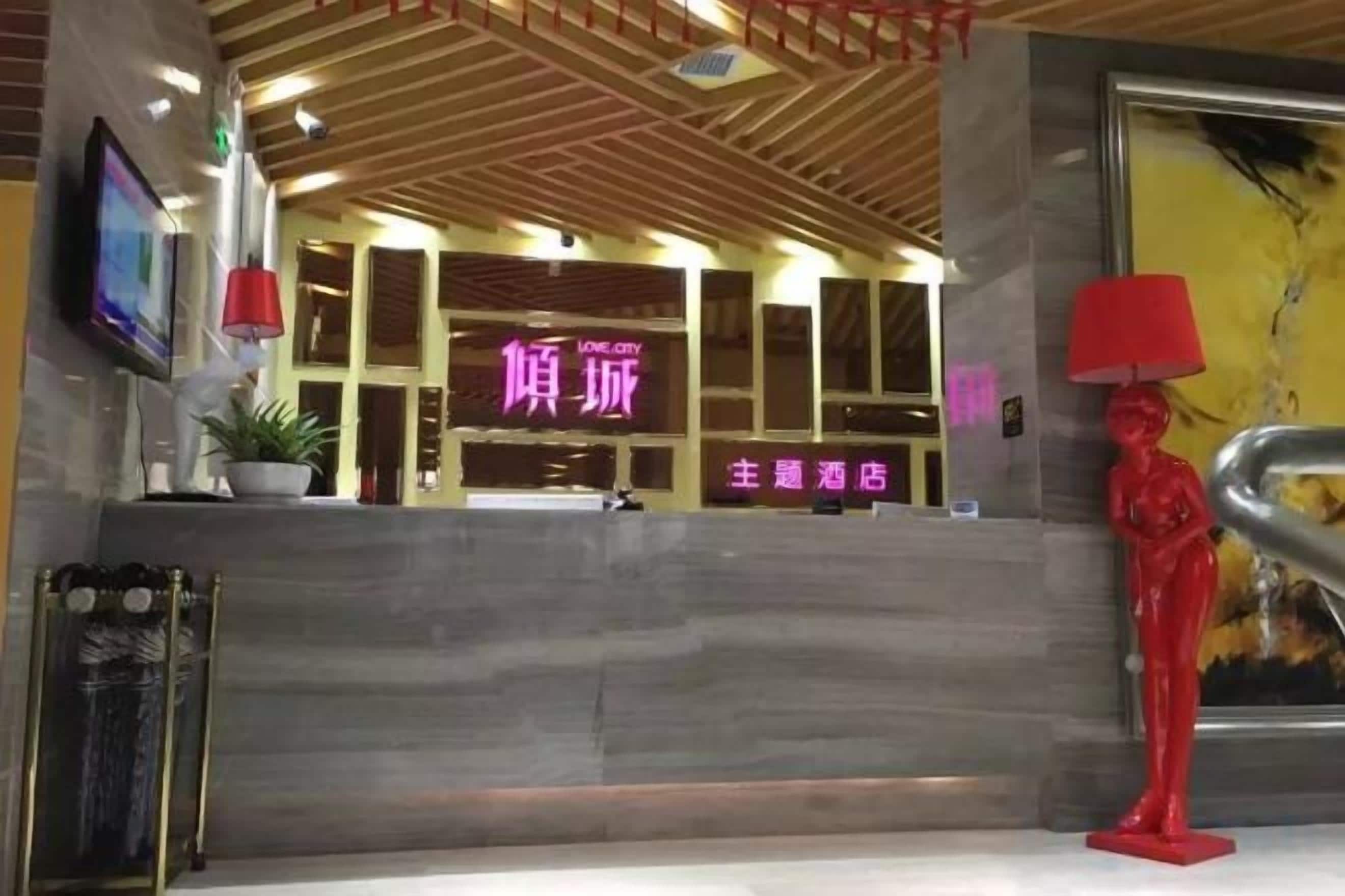 A hotel reception area with a modern design, featuring a reception desk, a red statue, and a large framed artwork on the wall.