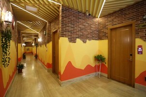 Un pasillo de hotel con pared de ladrillo, techo de madera y una puerta de madera.