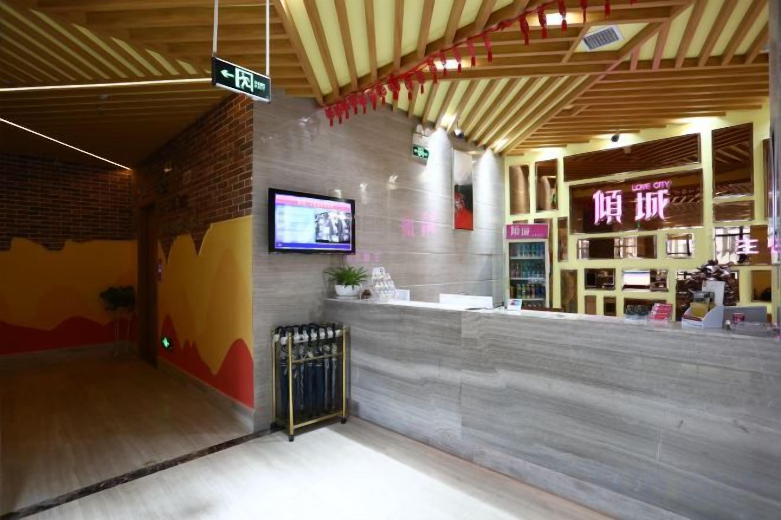 A reception area with a counter, a television mounted on the wall, and a sign indicating the direction to the bathroom.